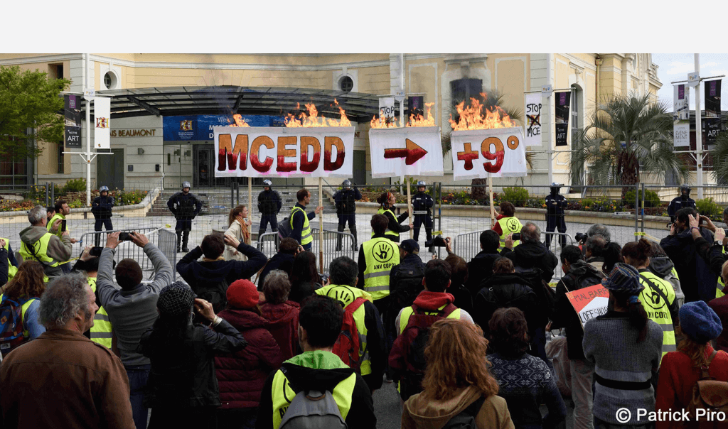 Banderole enflammée par les militants devant le Palais Beaumont, où se tenait le MCEDD, sous la protection permanente des forces de l'ordre