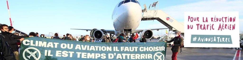 Foule de militants devant un avion avec une banderole "Climat ou aviation, il faut choisir. Il est temps d'atterrir". Pour la réduction du trafic aérien #AvionsATerre