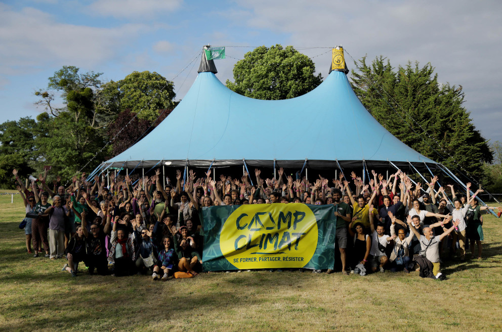 Plusieurs centaines de militantes posent devant un grand chapiteau avec une banderole "Camp Climat"