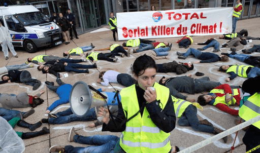 Personnes simulant une scène de crime symbolique (corps entourés de craie) pour le climat avec une affiche "Total : Serial Killer du Climat !"