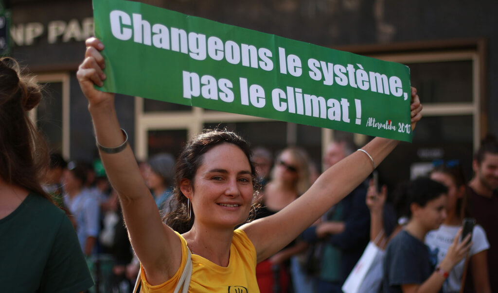 Une militante avec une banderole "Changeons le système, pas le climat !"