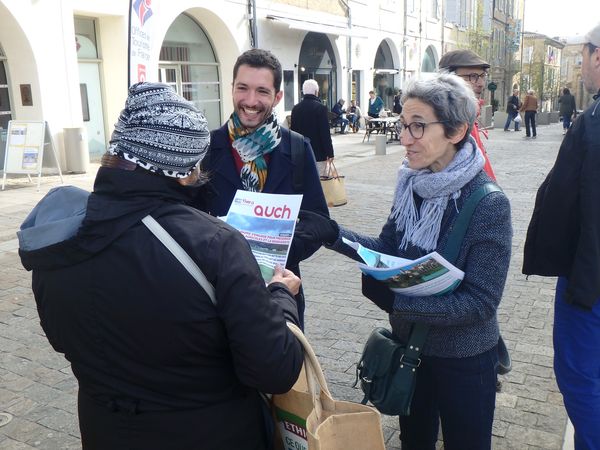 Deux militants souriants distribuent des magazines à une passante