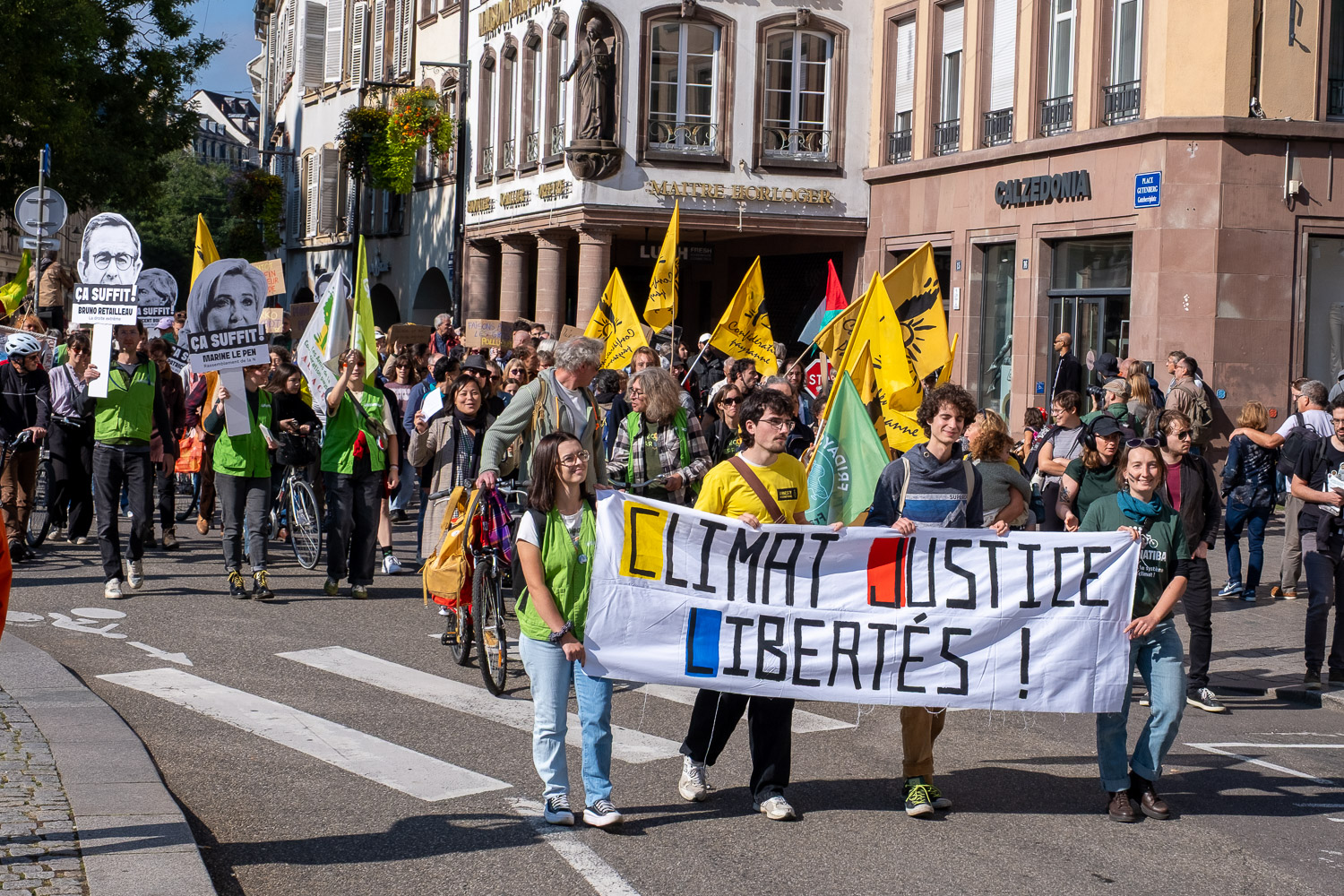 Cortège de manifestation défilant derrière une banderole Climat Justice Libertés