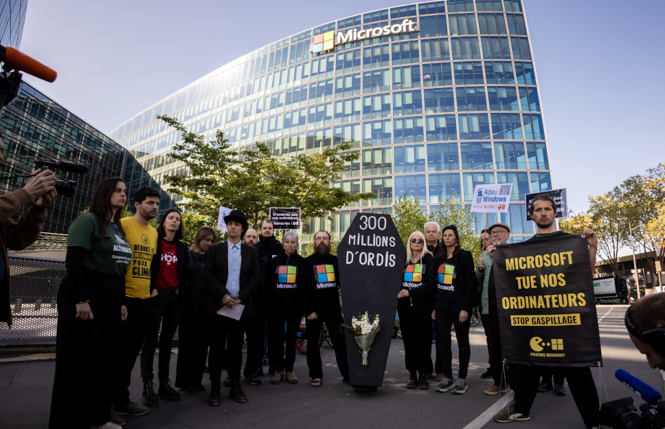 Enterrement de 300 millions d'ordinateurs devant le siège de Microsoft France à Issy-les-Moulineaux. On peut lire le message "Microsoft tue nos ordinateurs" sur une banderole et un cercueil "30 millions d'ordis".  